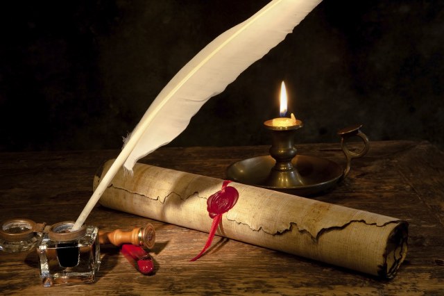 Quill pen in an inkwell with sealing wax and a parchment letter.